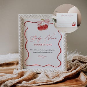 May include: White framed sign with a red border and a cherry graphic. The sign says "Baby Name Suggestions" and asks guests to write down baby name suggestions for the parents-to-be.