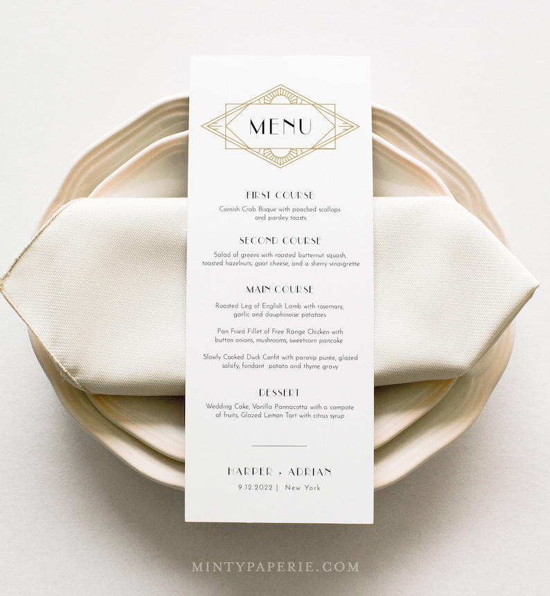 May include: A rectangular menu card with a gold geometric design at the top, featuring the word "MENU". The menu lists a multi-course meal, including Cornish Crab Bisque, Roasted Leg of English Lamb, and a Glazed Lemon Tart. The card is on a beige plate with a folded napkin.