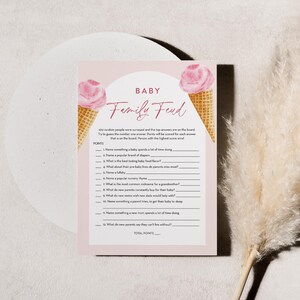 Puede incluir: Una tarjeta de juego de baby shower imprimible rosa y blanca con el t&iacute;tulo "Baby Family Feud". La tarjeta presenta dos conos de helado con helado rosa y conos de waffle. El juego pide a los jugadores que adivinen las mejores respuestas a preguntas sobre beb&eacute;s.