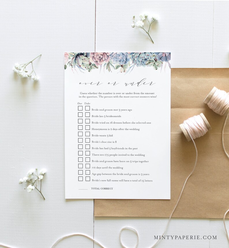 May include: A white card with a watercolor floral design at the top, featuring succulents in shades of blue, pink, and green. The card is a wedding game, with questions about the bride and groom. Two spools of pink thread and sprigs of white flowers are also in the image.