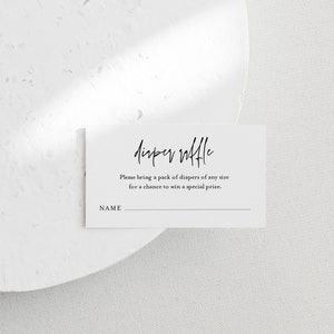 May include: A white card with black text that reads "Diaper Raffle". The text below says "Please bring a pack of diapers of any size for a chance to win a special prize." There is a blank line for a name.