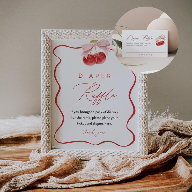 May include: White framed sign with a red and white cherry graphic and the text "DIAPER Raffle". The sign says "If you brought a pack of diapers for the raffle, please place your ticket and diapers here. Thank you".
