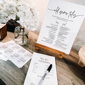 May include: A white sign with black text that reads "Old Wives Tales" and lists common pregnancy symptoms for both boys and girls. The sign is on a wooden easel and there are several stickers that say "Team Girl" on a table.