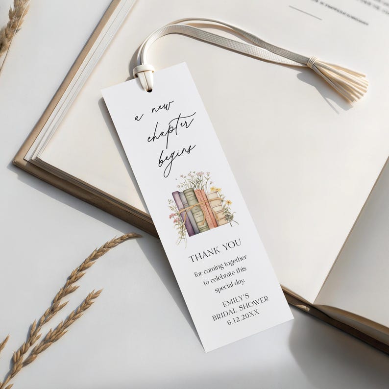 Peut inclure: Marque-page blanc avec un pompon cr&egrave;me, avec le texte "a new chapter begins". En dessous, une illustration &agrave; l'aquarelle de livres et de fleurs. Le bas du marque-page indique "THANK YOU" et les d&eacute;tails d'une bridal shower.