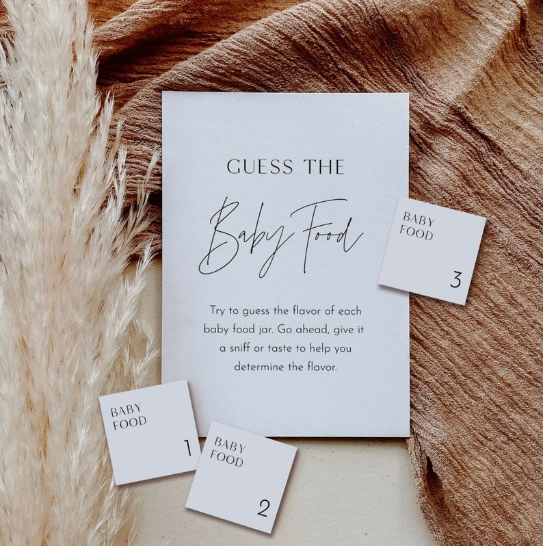 May include: A white card with the text "Guess the Baby Food" and instructions to guess the flavor of each baby food jar. Three white cards with the text "Baby Food" and numbers 1, 2, and 3.