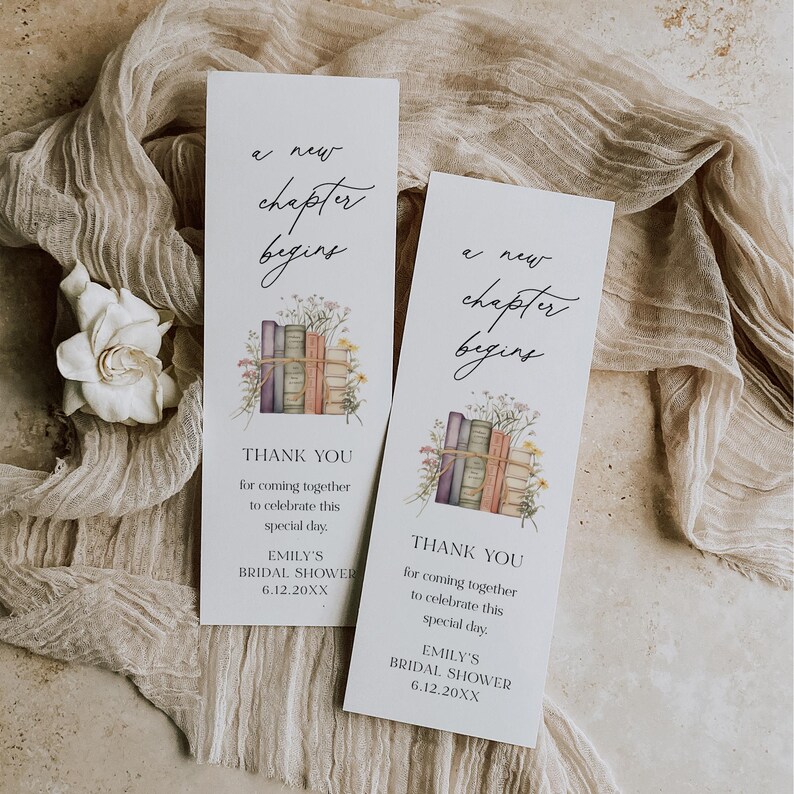 Peut inclure: Deux marque-pages blancs avec le texte "a new chapter begins" en &eacute;criture &eacute;l&eacute;gante. Chaque marque-page pr&eacute;sente une illustration &agrave; l'aquarelle de livres empil&eacute;s attach&eacute;s avec de la ficelle et des fleurs sauvages. Le texte "THANK YOU" et les d&eacute;tails de l'&eacute;v&eacute;nement sont &eacute;galement inclus.