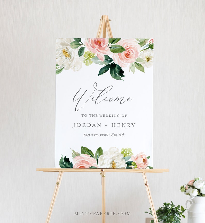 May include: A wedding welcome sign with a floral design featuring pink and white flowers. The sign reads "Welcome to the wedding of Jordan + Henry, August 23, 2020, New York".