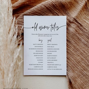May include: A white card with black text listing old wives' tales about pregnancy symptoms for a baby boy or girl. The card includes symptoms like salty cravings, round belly, no morning sickness, headaches, relaxed mood, sleep on left, cold and icy, glowing, clumsy, heart rate below 140, carrying low, swollen legs and ankles, sweet cravings, wide belly, morning sickness, no headaches, moody, sleep on right, hot and sweaty, acne and blemish, graceful, heart rate above 140, carrying high, little to no swelling.