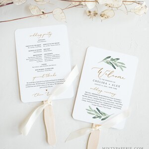 May include: A white wedding program fan with a green olive branch design and gold lettering. The text reads "Welcome to the wedding of Chelsea + Alex August 14, 2020 New York".