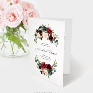 May include: Wedding program template with a burgundy, blush, and navy floral wreath. The text reads "Welcome to the wedding of Jurd and Elward, August 23, 2019, Mountainville Manor, Middletown, NY".
