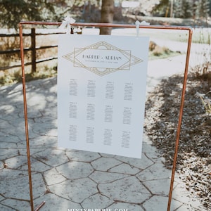 May include: A white wedding seating chart with gold geometric design and the names "Harper & Adrian" displayed on a copper pipe stand. The chart lists guest names by table number. The text "September 18, 2021 | New York" is also visible.