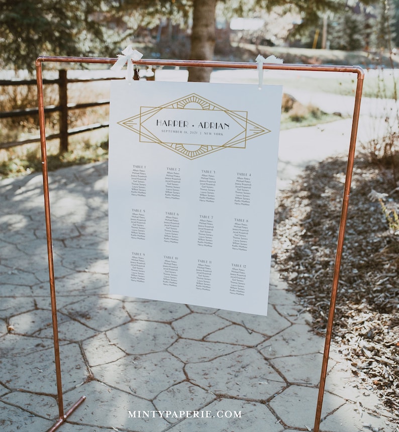May include: A white wedding seating chart with gold geometric design and the names "Harper & Adrian" displayed on a copper pipe stand. The chart lists guest names by table number. The text "September 18, 2021 | New York" is also visible.