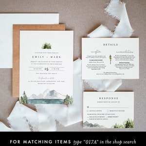 May include: A wedding invitation suite with a watercolor illustration of a mountain lake and forest. The invitation features the names "Emily & Mark" and the date "August 15, 4:30 PM". The RSVP card includes a choice of "Joyfully Accepts" or "Regretfully Declines" and a list of meal options.