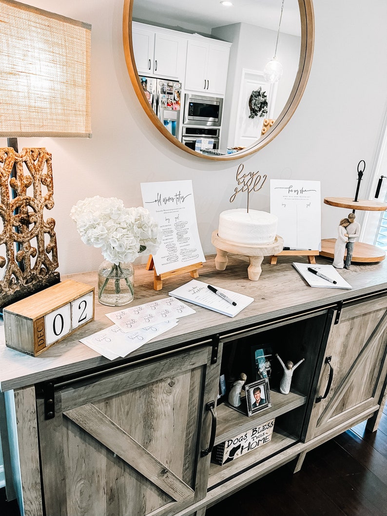 May include: A wooden table with a rustic finish, decorated for a baby shower. There is a cake with a "baby girl" topper, a sign that says "old wives tales", and a sign that says "boy or girl". There is also a wooden block calendar that says "Dec 02".