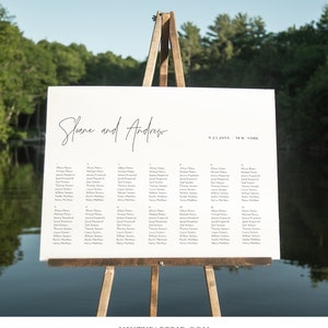 May include: A white wedding seating chart with black text. The chart is on an easel and lists the names of guests assigned to each table. The chart is titled "Sloane and Andrew" and includes the date "9.23.20XX" and location "NEW YORK".