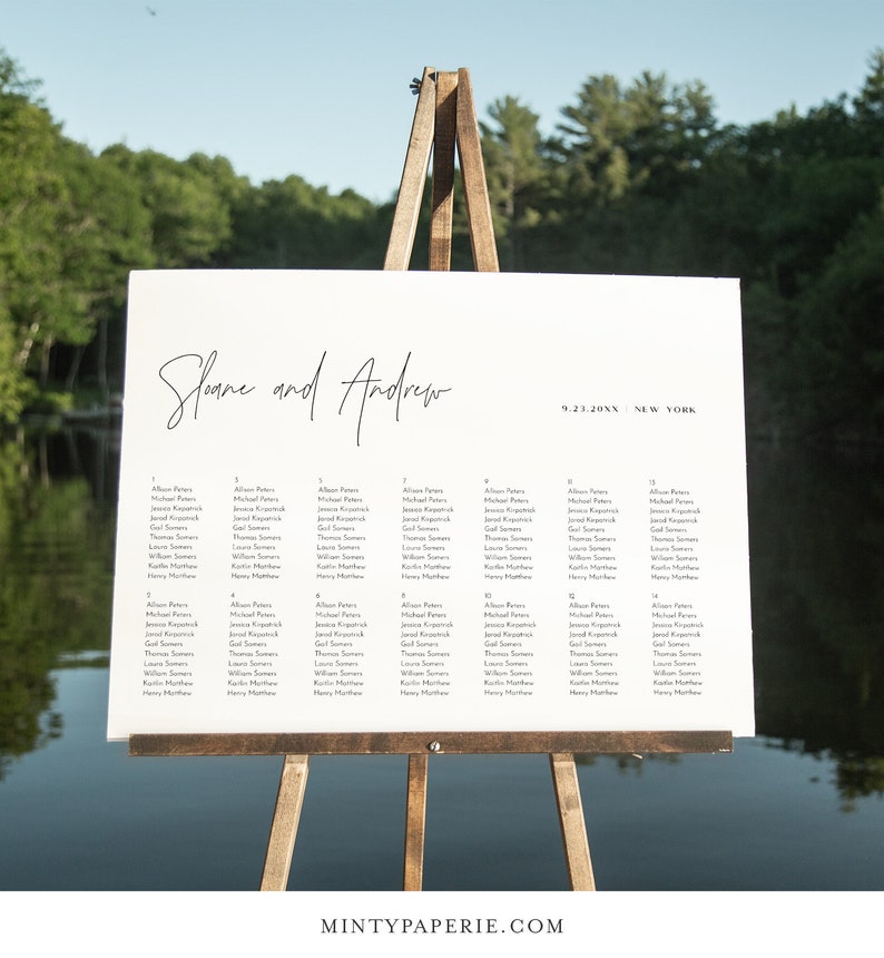 May include: A white wedding seating chart with black text. The chart is on an easel and lists the names of guests assigned to each table. The chart is titled "Sloane and Andrew" and includes the date "9.23.20XX" and location "NEW YORK".