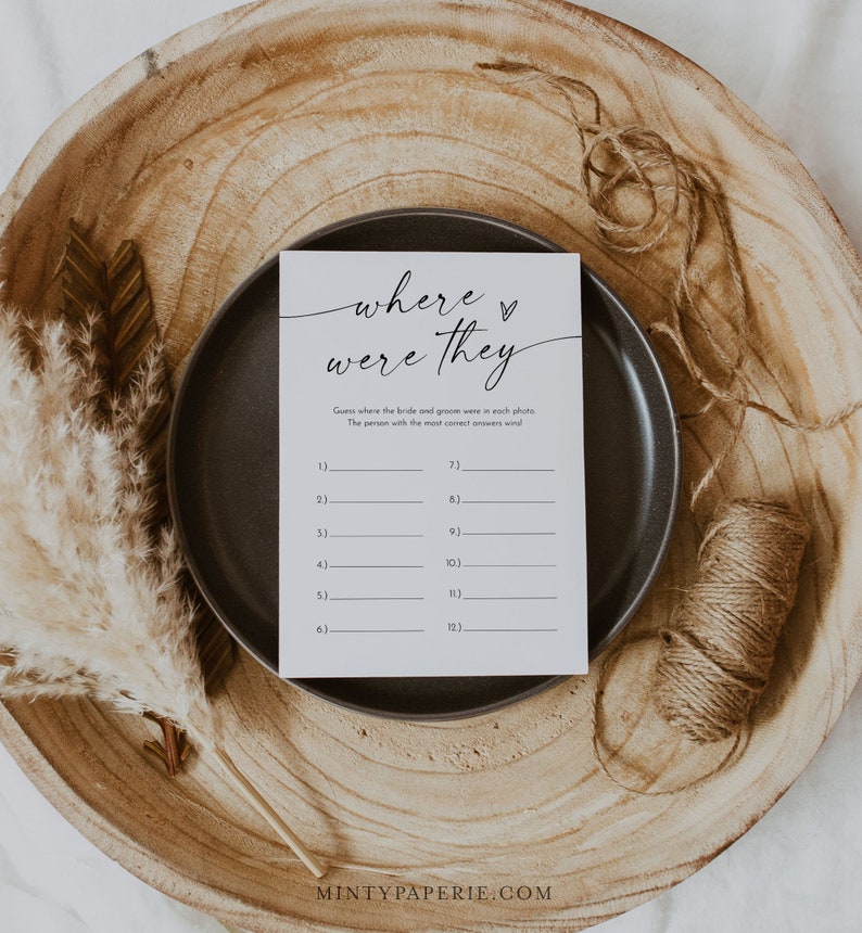 Puede incluir: Una tarjeta de juego de boda imprimible con el texto "d&oacute;nde estaban" en una fuente manuscrita. La tarjeta tiene un espacio en blanco para 12 fotos y pide a los invitados que adivinen d&oacute;nde estaban la novia y el novio en cada foto.