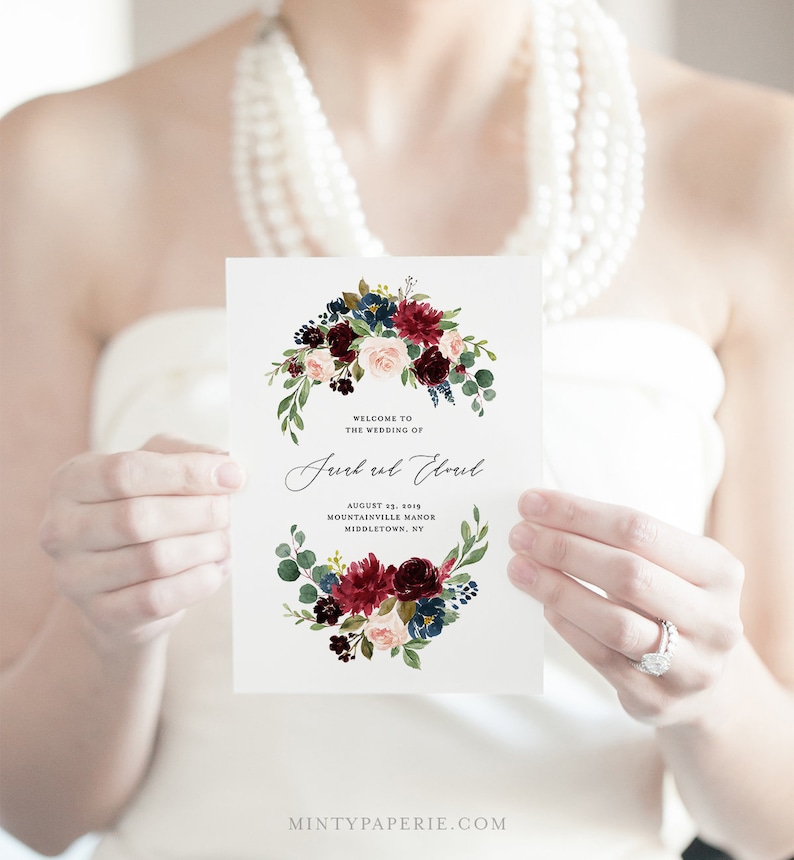 May include: Wedding invitation with a watercolor floral design in shades of burgundy, pink, and blue. The text reads "Welcome to the wedding of Jurk ul Eloul, August 23, 2019, Mountainville Manor, Middletown, NY".