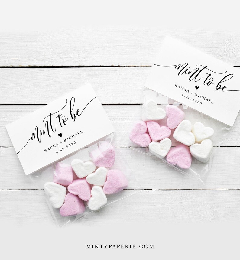 K&ouml;nnte beinhalten: Zwei durchsichtige Plastikt&uuml;ten gef&uuml;llt mit rosa und wei&szlig;en herzf&ouml;rmigen Marshmallows. Jede T&uuml;te hat ein wei&szlig;es Etikett mit schwarzem Text, auf dem "mint to be" mit einem kleinen schwarzen Herzen und den Namen "Hanna + Michael" sowie dem Datum "9.22.2020" steht.
