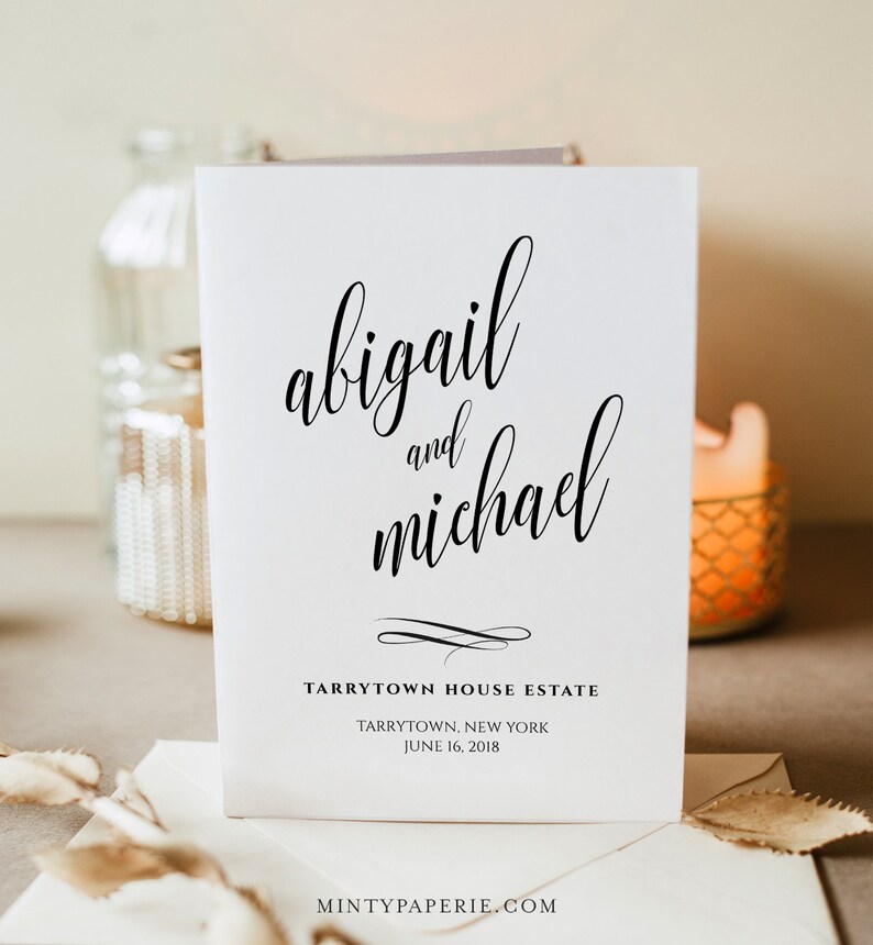 以下が含まれることがあります： 白い結婚式の招待状に、黒い書体で「abigail and michael」と書いてあり、その下に「Tarrytown House Estate, Tarrytown, New York, June 16, 2018」と書いてあります。