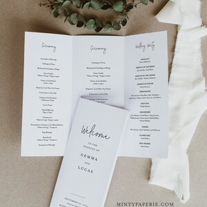 Può includere: Un programma di nozze bianco con un design semplice. La copertina anteriore presenta il testo "Benvenuti al matrimonio di Gemma e Lucas" con la data e la posizione stampate sotto. Le pagine interne elencano l'ordine della cerimonia e la festa di nozze.