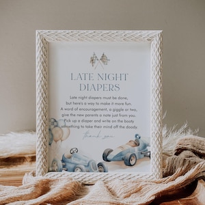 May include: A white framed sign with blue text that reads "Late Night Diapers". The sign has a blue and white checkered flag design and a watercolor illustration of two blue race cars.
