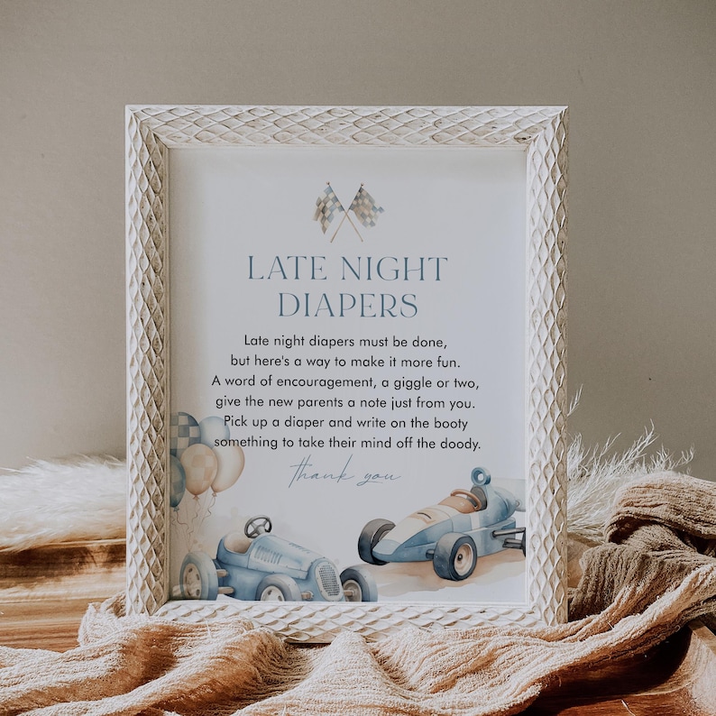 May include: A white framed sign with blue text that reads "Late Night Diapers". The sign has a blue and white checkered flag design and a watercolor illustration of two blue race cars.