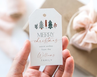 Könnte beinhalten: Ein weißes Weihnachtsgeschenkanhänger mit festlichem Design. Der Anhänger zeigt illustrierte Bäume in Grün, Braun und Rot. Die Worte "MERRY christmas" sind in einer Mischung aus Schriftarten geschrieben, mit "Williams FAMILY" unten. Die Website-Adresse befindet sich unten.