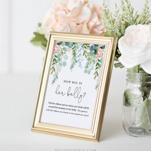 May include: A white card with a floral design in shades of pink, green, and blue. The card has the text "HOW BIG IS her belly?" and instructions for a baby shower game.