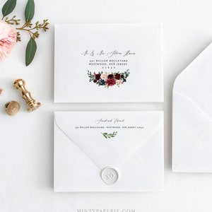 May include: Two white envelopes with calligraphy addressing. The top envelope has a floral design with burgundy, pink, and blue flowers. The bottom envelope has a wax seal with the letters XO.