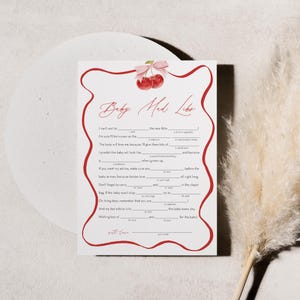 May include: A printable baby shower game with a red border and cherries. The game is called "Baby Mad Libs" and has fill-in-the-blank spaces for guests to complete.