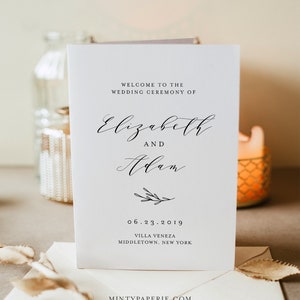 May include: A white wedding ceremony programme with black calligraphy text. The programme reads "Welcome to the Wedding Ceremony of Elizabeth and Adam" with the date "06.23.2019" and the location "Villa Veneza, Middletown, New York".