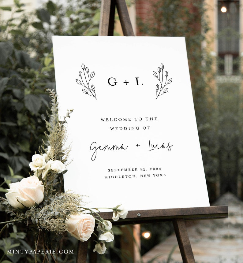 May include: A white wedding welcome sign with black text and simple floral illustrations. The sign reads "Welcome to the Wedding of Gemma + Lucas, September 23, 2020, Middleton, New York".