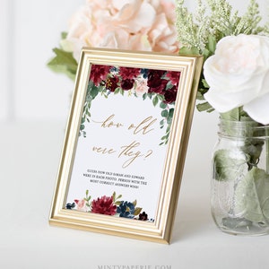 May include: A printable wedding game card with a floral design in shades of burgundy, pink, and blue. The text reads "How old were they?" and "Guess how old Sarah and Edward were in each photo. Person with the most correct answers wins!"