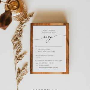 May include: A wooden framed RSVP card with a handwritten RSVP in cursive. The card has a checklist for guests to indicate their attendance and a list of entree options.