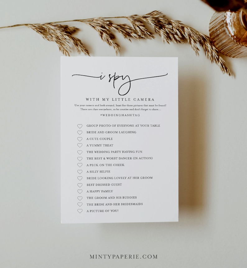 May include: A printable wedding game card with the title "I Spy with my little camera" and a list of things to find at a wedding, such as "bride and groom laughing", "a cute couple", and "a picture of you!"