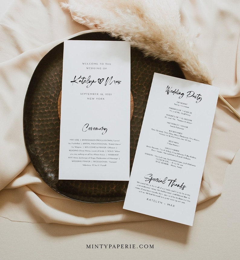 May include: A white wedding ceremony programme with the names Katelyn and Max and the date 18 September 2021. The programme lists the order of events for the ceremony, including the processional, welcome and prayer, reading, vows, and recessional.