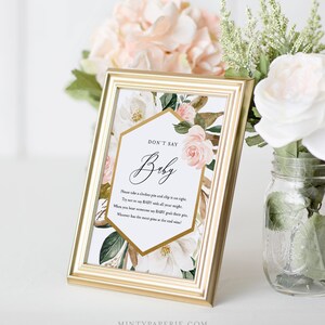 May include: A printable game card with a floral design and gold accents. The card has the text "Don't Say Baby" and instructions for a game.