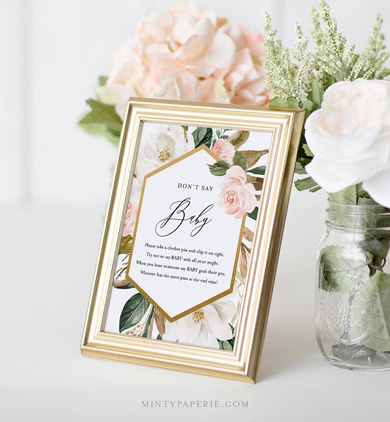 May include: A printable game card with a floral design and gold accents. The card has the text "Don't Say Baby" and instructions for a game.