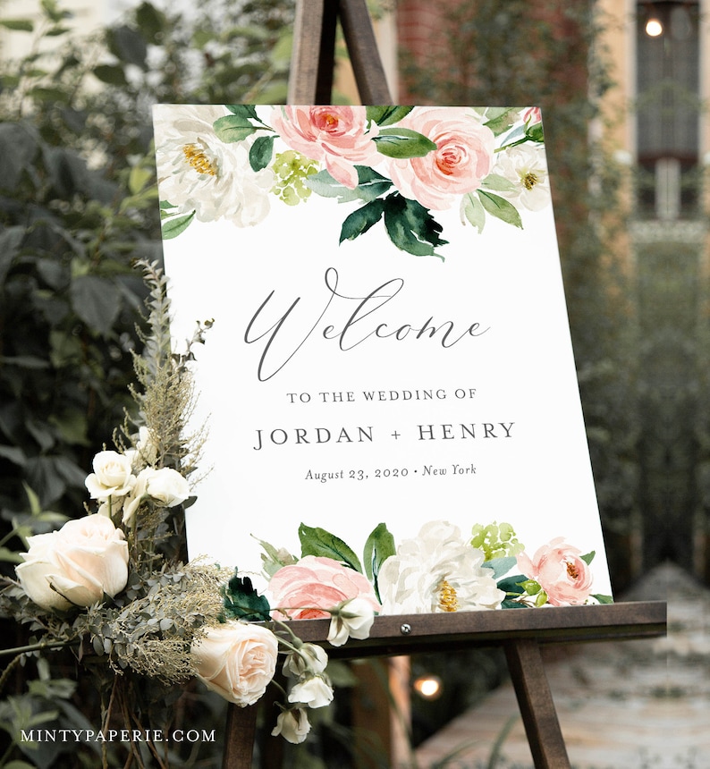 May include: A wedding welcome sign with a floral design featuring pink and white flowers. The sign reads "Welcome to the wedding of Jordan + Henry, August 23, 2020, New York".