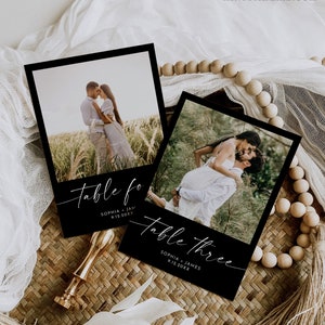May include: Two black and white table cards with a photo of a couple and the text "Table Four Sophia - James 9.12.20XX" and "Table Three Sophia - James 9.12.20XX".