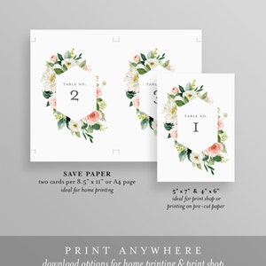 May include: Two printable table number cards with floral designs. The cards feature a hexagonal frame with the table number in the center. The floral design includes white and pink flowers with green leaves. The text on the cards reads "Table No. 2" and "Table No. I".