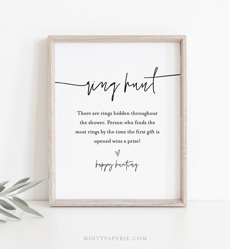 May include: A printable sign with the text "ring hunt" in cursive script. The sign instructs guests to find rings hidden throughout the shower, with the person who finds the most rings by the time the first gift is opened winning a prize. The sign also includes the text "happy hunting" in cursive script.