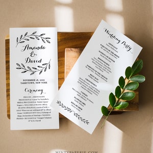 May include: A wedding ceremony program with a black and white floral design. The program lists the officiant, wedding party, and ceremony details. The text includes the names Amanda and David, the date November 18, 20XX, and the location Tarrytown, New York.