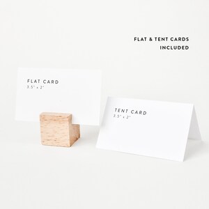 May include: Two blank white cards, one flat and one folded into a tent shape, with the dimensions 3.5 inches by 2 inches printed on each. The cards are displayed on a white surface with a small wooden block holding the flat card.