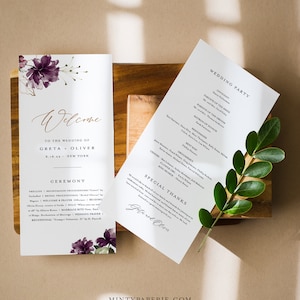 May include: Wedding ceremony program with a purple floral design. The program includes the wedding party, ceremony details, and a special thanks section. The text reads "Welcome to the wedding of Greta + Oliver 6.18.22 New York".