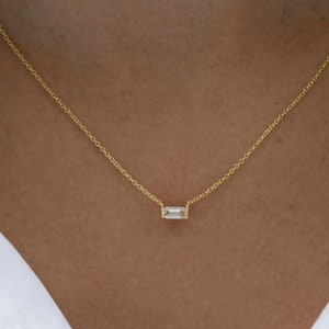May include: A delicate gold chain necklace with a small, rectangular, clear gemstone pendant. The necklace is shown on a model wearing a white shirt. The text "Small Size" is visible in the bottom right corner of the image.