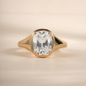 Front view of an elongated cushion cut cubic zirconia ring in gold, showing the tapered band and bezel-set stone.