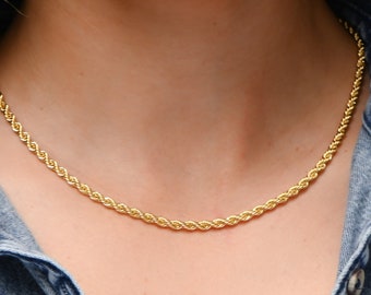 May include: A gold rope chain necklace on a model wearing a denim shirt.