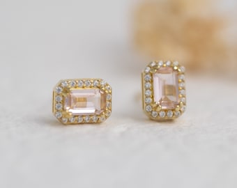 May include: A pair of gold earrings with a pink gemstone set in a square shape with a halo of smaller diamonds.